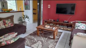 sala de estar con 2 sofás y TV de pantalla plana en Recanto dos Pássaros, en Ilhabela