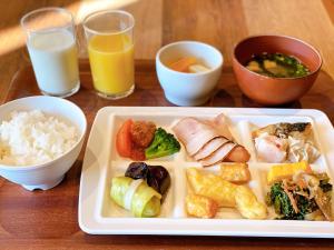 a plate of food on a table with rice and orange juice at Henn na Hotel Maihama Tokyo Bay in Urayasu