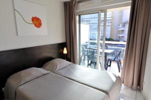 a bedroom with a bed and a balcony with a table at Residhotel Cannes Festival in Cannes