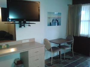 een kamer met een tafel en stoelen en een televisie aan de muur bij Elsinor Motor Lodge in Wollongong