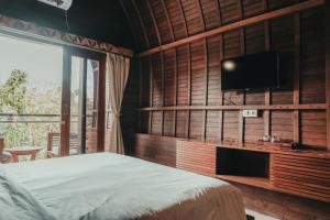 a bedroom with a bed and a flat screen tv at Sekar Arum Riverside Resort in Canggu in Tanah Lot