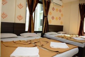 a couple of beds in a room with curtains at Hotel Sai Sampada NX in Shirdi