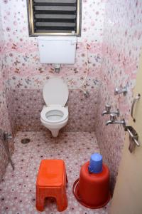 een badkamer met een toilet en een rode kruk bij Hotel Sai Sampada NX in Shirdi