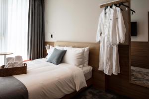 釜山的住宿－Sangsang Stay Busan，酒店客房设有一张床和挂在墙上的长袍