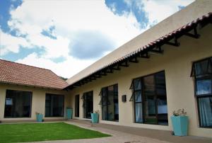 a building with windows and a grass yard at Mahem Manor Guesthouse in Brits