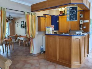 a kitchen with wooden cabinets and a dining room at Hotel Zsida in Szentgotthárd