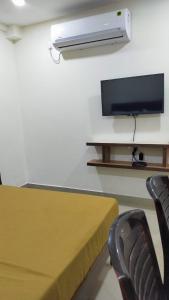 Habitación con TV, mesa y sillas. en Bhumi Residency, en Mangalore