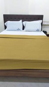 a yellow bed with two pillows on top of it at Bhumi Residency in Mangalore