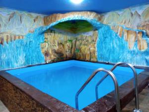 a swimming pool in a cave with a painting on the wall at Хамам Вілла Даросо з басейном in Kosiv