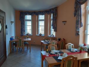 Pension Schöne في Großröhrsdorf: غرفة طعام مع طاولات وكراسي ونوافذ