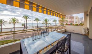 a balcony with a view of the beach and palm trees at R114 Apartment Ca La Laura in Calafell