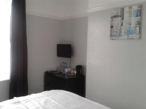 a bedroom with a bed and a desk with a television at South Rising Guest House in Poole