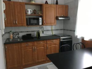 cocina con armarios de madera, fregadero y fogones en Pálma apartman en Szentes