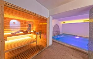 a woman sitting in a sauna next to a swimming pool at Family Spa Hotel Le Canne in Ischia