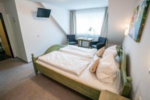 a bedroom with a bed with two chairs and a table at Hotel-Gasthof zur Linde in Langenau