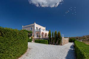 uma casa numa colina com arbustos e árvores em Villa Casa Del Sol Syros em Parakopí