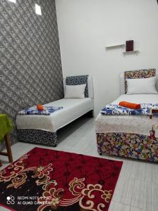ブキティンギにあるPenginapan Rezki Syariahのベッド2台、ソファ、ラグが備わる客室です。