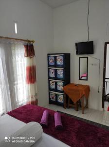 a bedroom with a bed and a table and a television at Penginapan Rezki Syariah in Bukittinggi