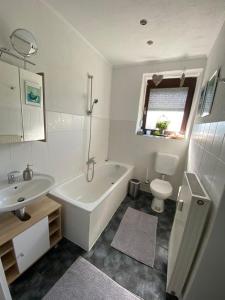 a bathroom with a tub and a toilet and a sink at Ferienwohnung am Theo Carlen Platz in Ormesheim