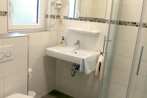 uma casa de banho branca com um lavatório e um chuveiro em Hotel Munzert em Hof