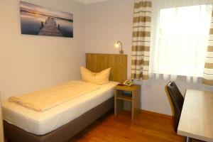 1 dormitorio con 1 cama con mesa y ventana en Hotel Munzert, en Hof