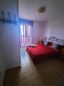 1 dormitorio con cama roja y ventana en Sunny Apartment, en Mojácar