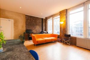 an orange couch in a living room with windows at GuestReady - Bright Studio in the Heart of London in London