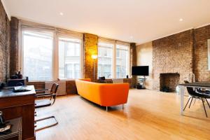a living room with an orange couch and a fireplace at GuestReady - Bright Studio in the Heart of London in London
