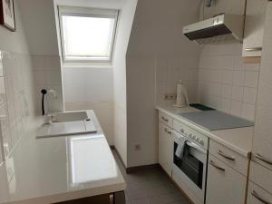 a white kitchen with a sink and a stove at Amadeus Apartment in Baden