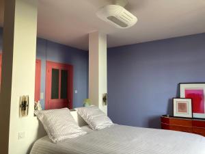 een slaapkamer met een blauwe muur en een bed met kussens bij Au Petit Thouars in Thouars