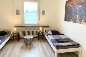 HauにあるApartments Bedburg-Hauのベッド2台、テーブル、窓が備わる客室です。