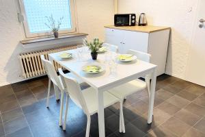 a white table with white chairs and a white refrigerator at Apartments Bedburg-Hau in Hau
