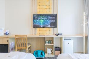 a room with a tv on a shelf and a chair at Henn na Hotel Kyoto Hachijoguchi in Kyoto