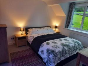 a bedroom with a bed and a window and two lamps at Beautiful 3-bed stone barn in idyllic Hawkshead in Hawkshead