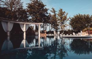 una piscina de agua con un pabellón y sillas en Hotel Relais, en San Bonifacio