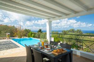 a table and chairs on a patio with a pool at Villa Belvedere Verde in Tsoukaladhes