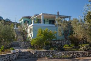 a blue house with a stone retaining wall at Villa Belvedere Verde in Tsoukaladhes