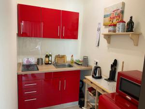 uma cozinha com armários vermelhos e um lavatório em Lichtdurchflutetes Apartment mit Blick ins Grüne em Mülheim an der Ruhr