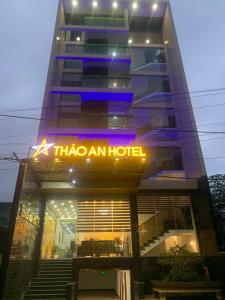 フエにあるTHẢO AN HOTEL Huếのネオンの看板が貼られた高層ビル