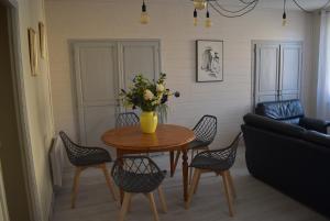 une table à manger avec des chaises et un vase de fleurs dans l'établissement Maison de charme dans le Gers, à Noilhan