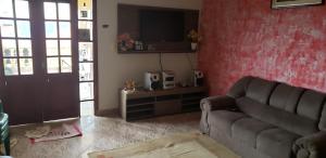 ein Wohnzimmer mit einem Sofa und einer roten Wand in der Unterkunft Casa Linda e Arejada in São Thomé das Letras