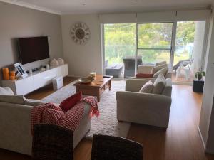 a living room with two couches and a tv at House Beside The Lake in Summerland Point