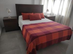 1 dormitorio con 1 cama grande con almohadas rojas en Departamento Ripozi Centro en Córdoba