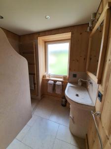 ein Bad mit einem Waschbecken und einem Fenster in der Unterkunft Chambres d'hôtes La Carrée in Les Fins