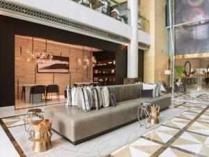 a lobby with a couch and a dining room at Hyatt Regency Al Kout Mall in Kuwait