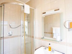 a bathroom with a shower and a sink and a mirror at The Castleton in Swanage