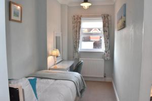 1 dormitorio con cama, escritorio y ventana en The Castleton en Swanage