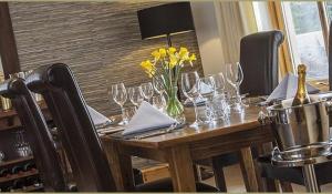 a wooden table with wine glasses and yellow flowers on it at Sutherlands Guest House in Kingussie