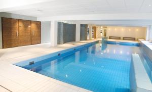 een groot zwembad met blauwe tegels in een gebouw bij Bilderberg Hotel De Bovenste Molen in Venlo