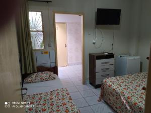 a hotel room with two beds and a television at Pousada Belo Mar in Maceió